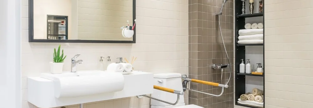 Modernes, barrierefreies Badezimmer mit Haltegriffen neben der Toilette und einem Waschbecken.